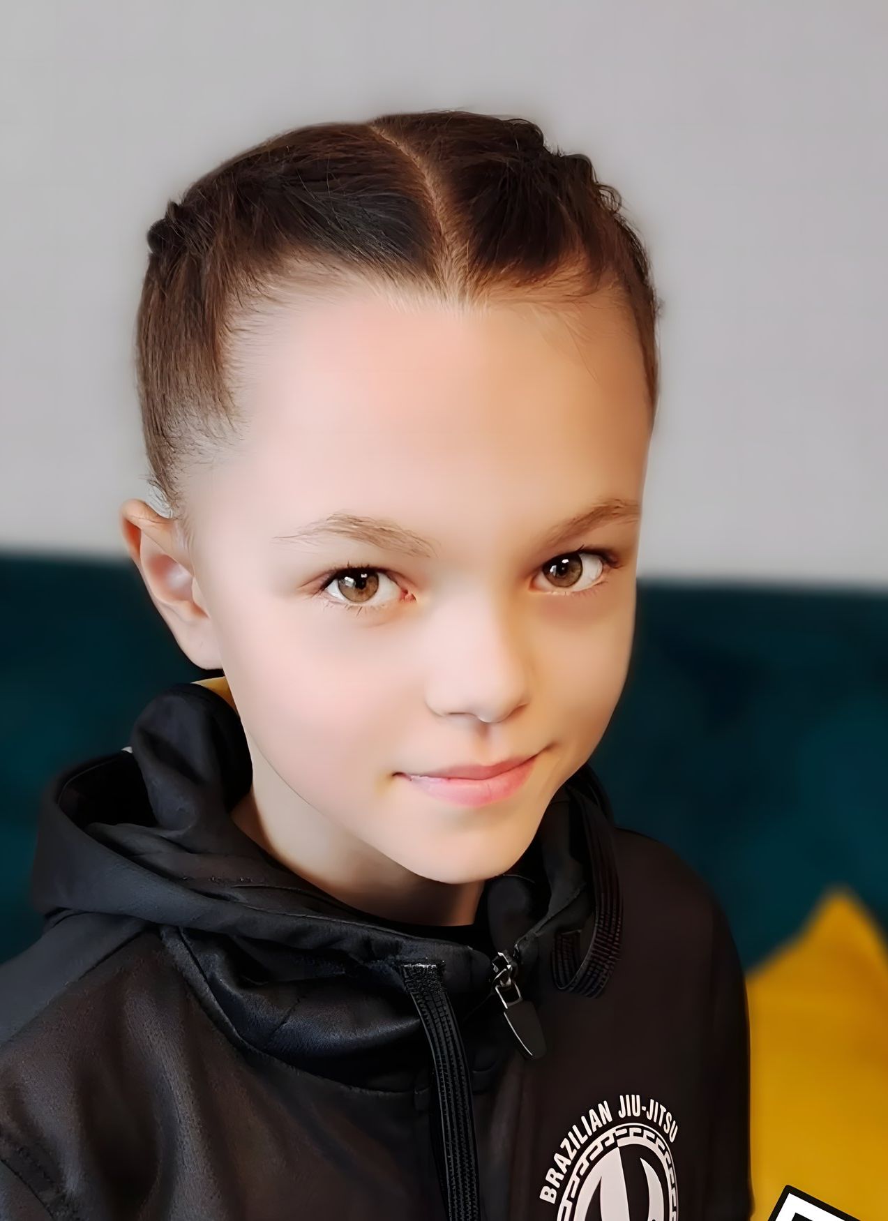 Portrét usměvavé Adély s copánky v černé sportovní mikině